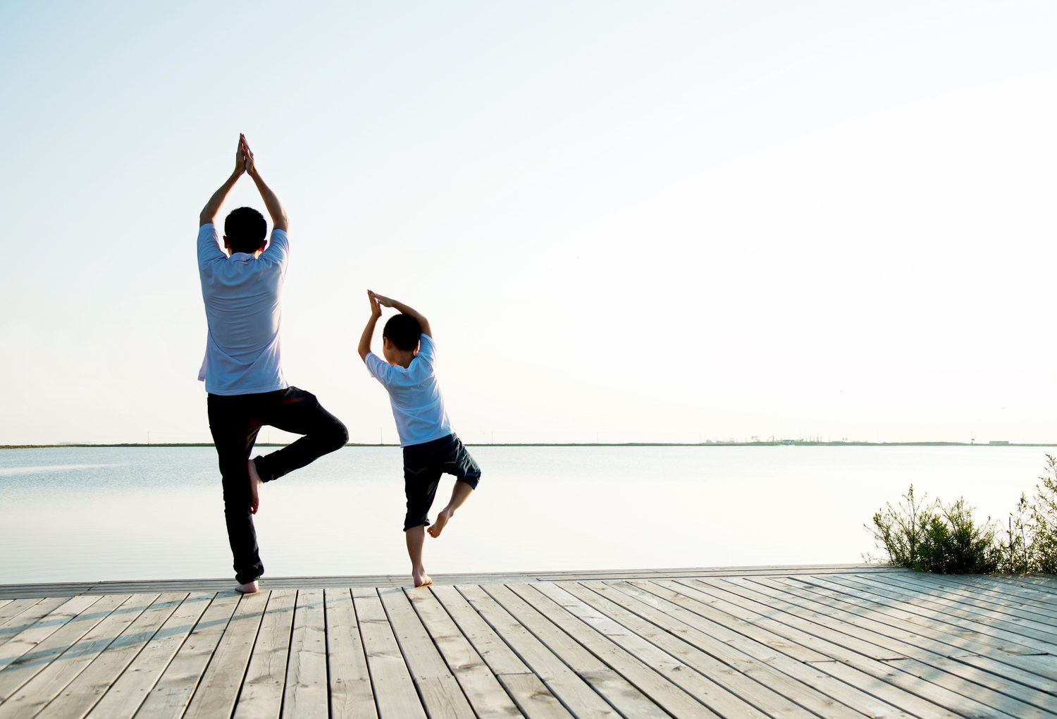 Father with his son doing yoga by the lake